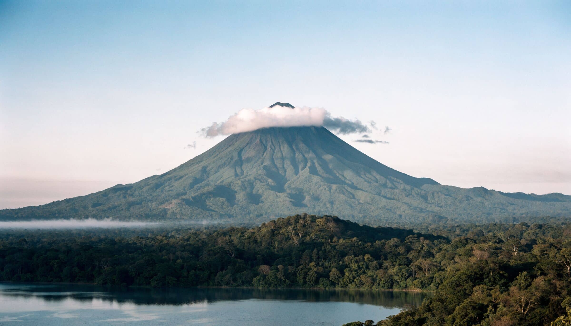 Le volcan Arenal coiffé d’un nuage, au-dessus de la forêt tropicale et du lac