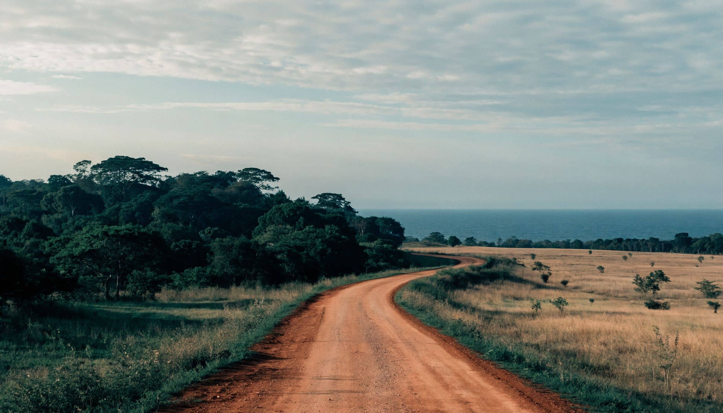 Une piste de terre rouge à travers la savane du Guanacaste, avec le Pacifique à l’horizon